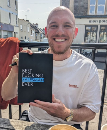Jack Walsh, founder of JWI Commercial, holding his book Best Fucking Salesman Ever.
